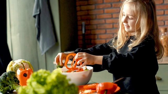 Kind bereitet Gemuese in der Kueche zu