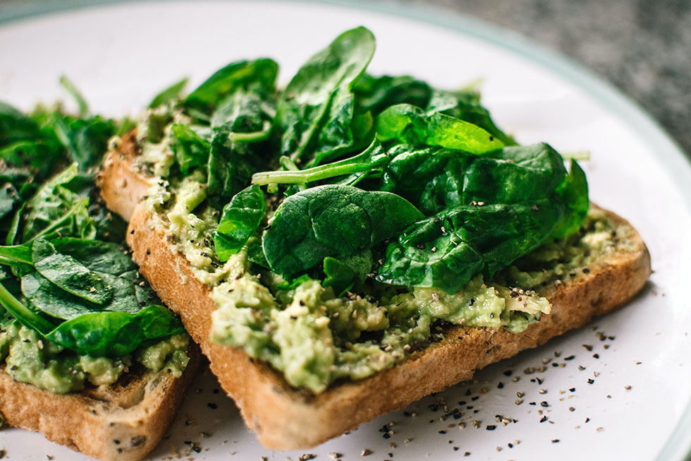 Veganes Pausenbrot mit Avocado und gruenen Blaettern.