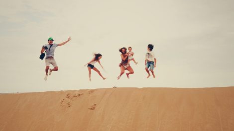 Familie springt auf Sanddüne