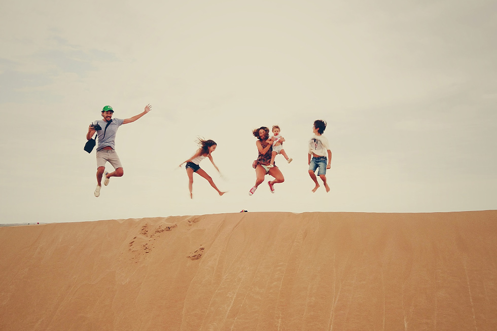 Familie springt auf Sanddüne